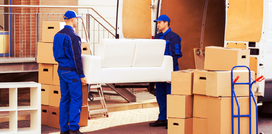 two men in blue uniform loading heavy furniture into the truck