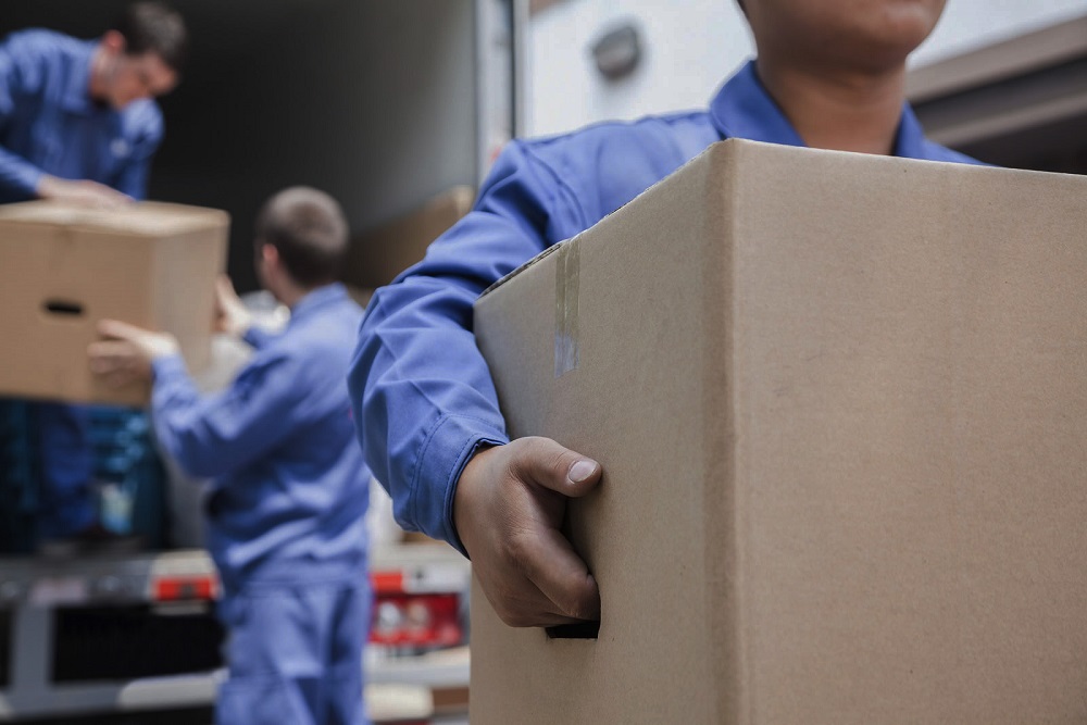 cropped image of men in blue uniform taking out boxes from moving truck