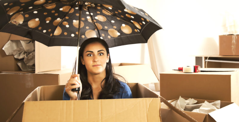 young girl holding an umbrella and sitting in a big packing box