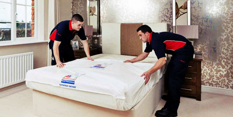 two men in uniform lifting mattress and heavy furniture