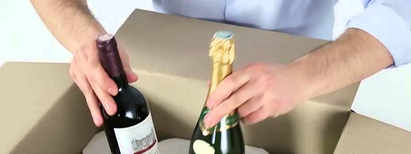 cropped image of a man packing liquor bottle in a cardbox