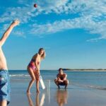 family playing cricket at a beach