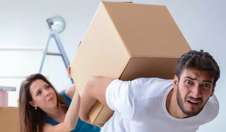 young man trying to lift a heavy box on his back