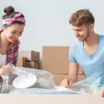 couple packing up kitchen supplies into a cardboard box
