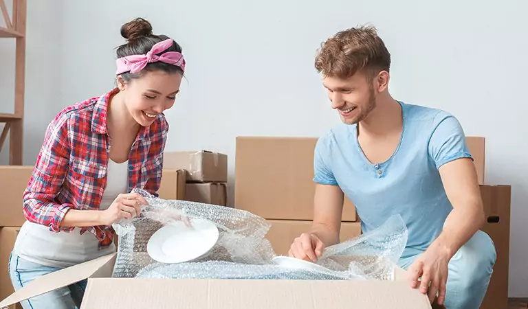 couple packing up kitchen supplies into a cardboard box
