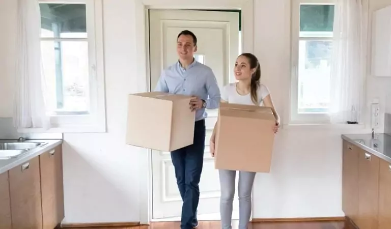couple with cardboard boxes inside of their new apartment