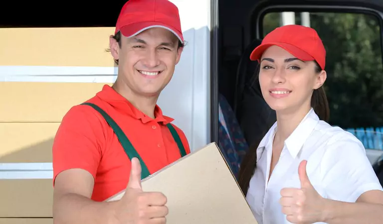 young professional couple with cardboard box showing thumbs up