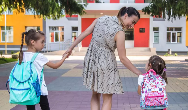 young woman outside of a school with her children