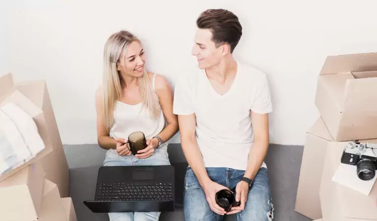 couple sitting on the floor and searching something on a computer