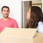 couple with some cardboard boxes inside of a house