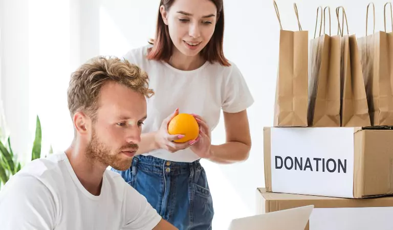 couple searching something on a computer and some cardboard boxes with donation tag
